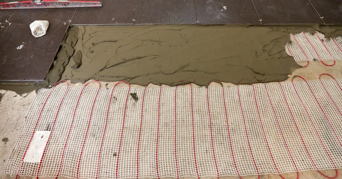 Dark brown 12x12 tile floor over red heated flooring system.